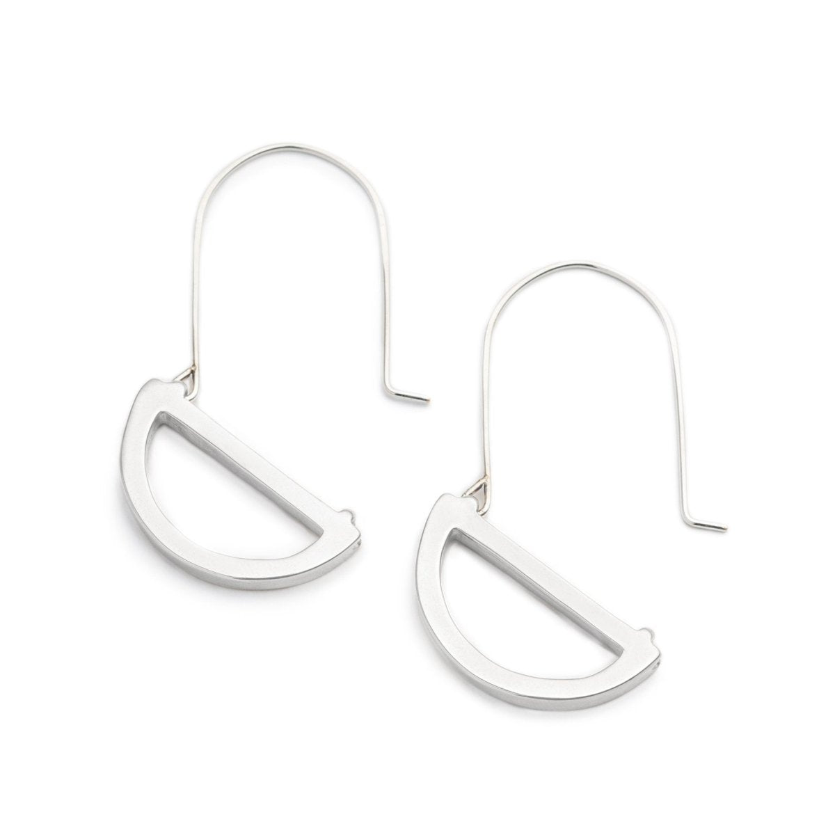 Modern, polished, cast silver semicircle pendants hanging below long, hand-formed, sterling silver hoops. Hand-crafted in Portland, Oregon.