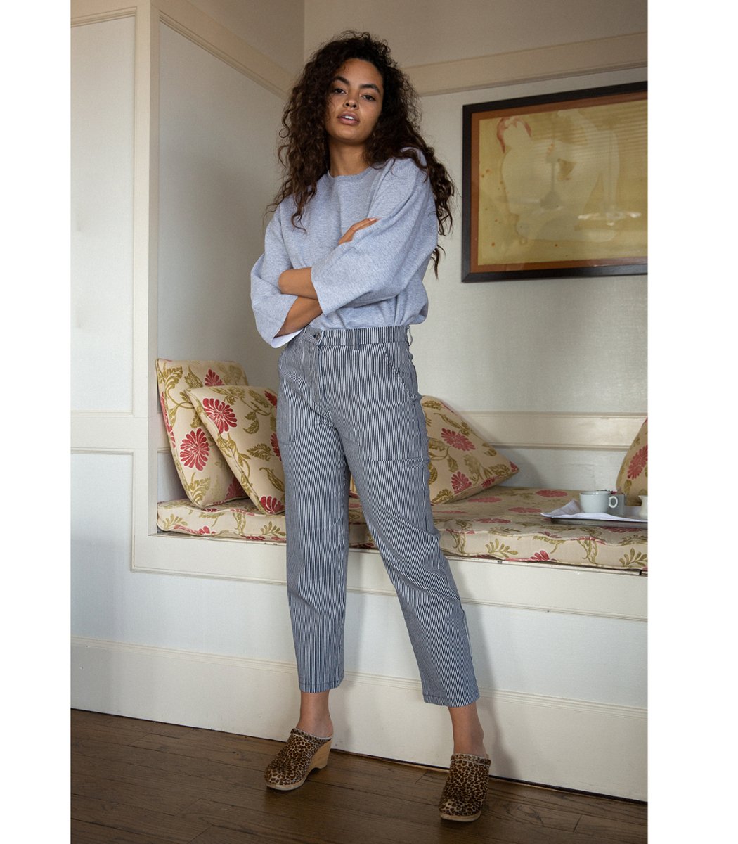 Model wears a straight leg work pant with a thin blue/grey striped pattern. The James Pant in Stripe is designed by Loup and made in New York City, USA.