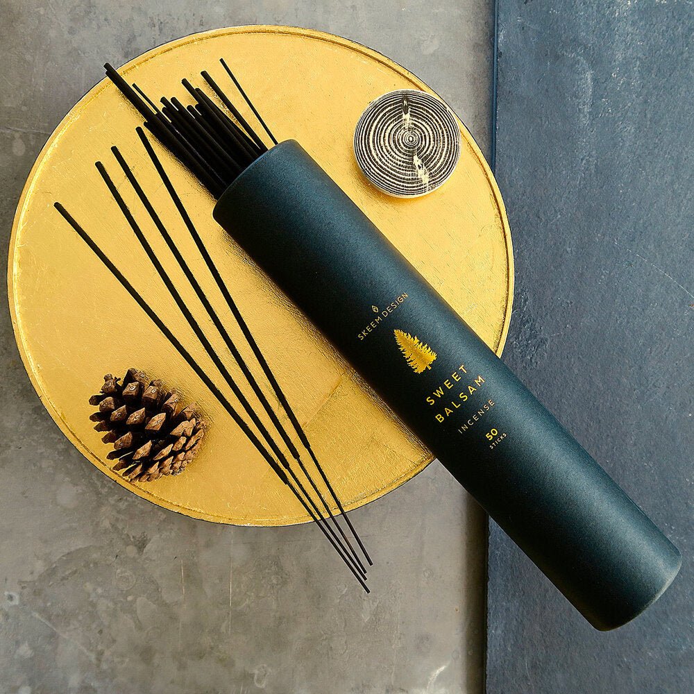 Black cylindrical packaging with a gold tree design. Contains fifty incense sticks in the scent sweet balsam. Made in Philadelphia, PA by SKEEM Design.