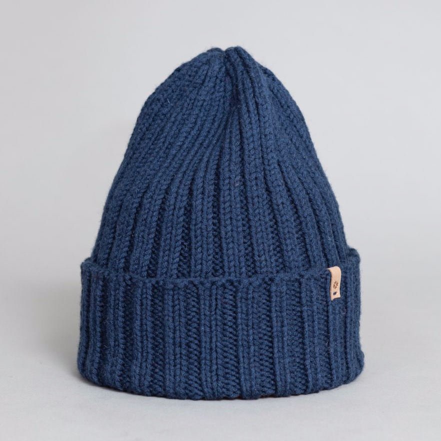 Dark blue cuffed hat with thick ribbed design and decrease detail at the top. The Merino Thick Rib Hat in Dark Blue is designed by Dinadi and hand knitted in Kathmandu, Nepal.