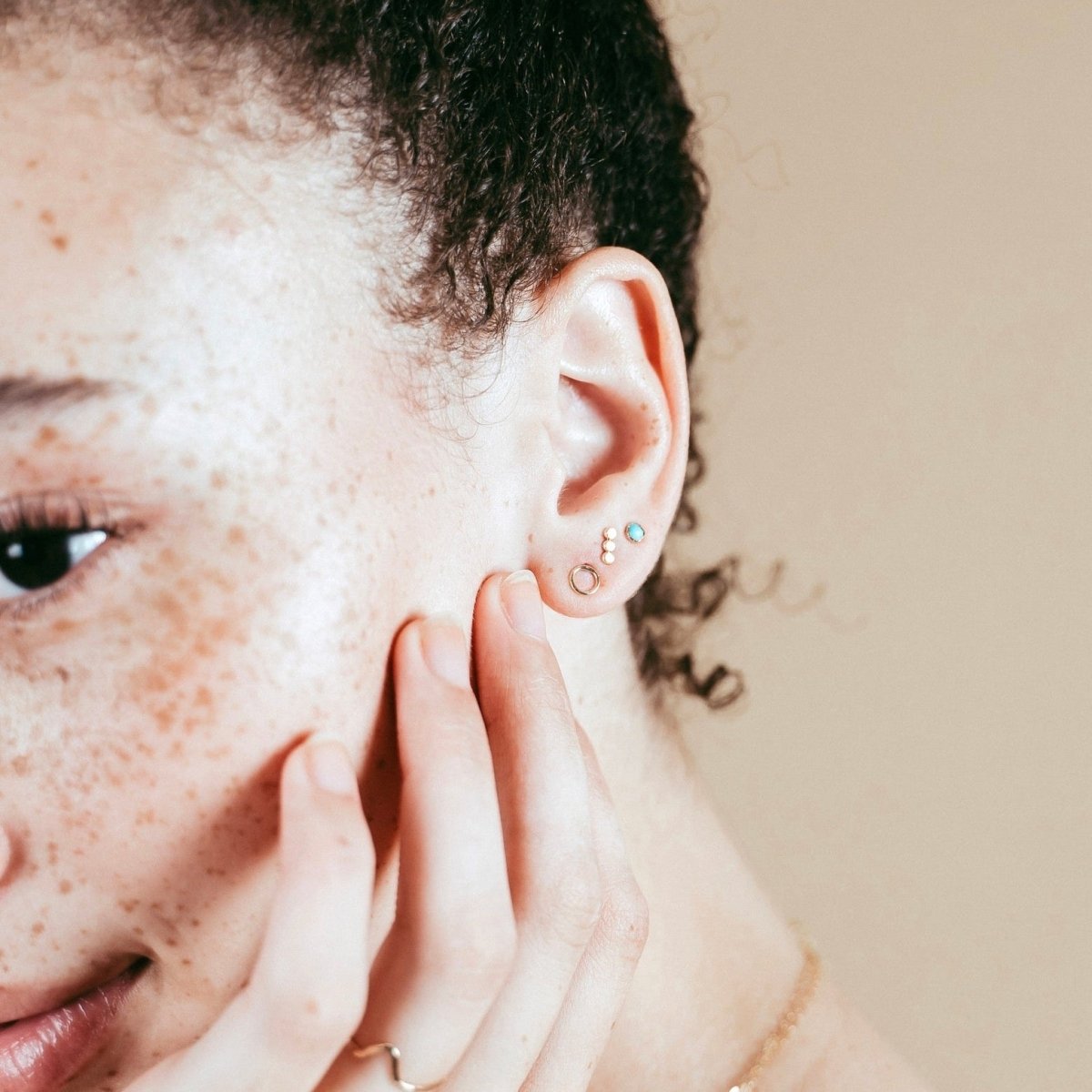 A model wears the gold fill three dot stud earrings. The Three Dot Studs are designed and handcrafted by Deivi Arts Collective in Vancouver, Canada.