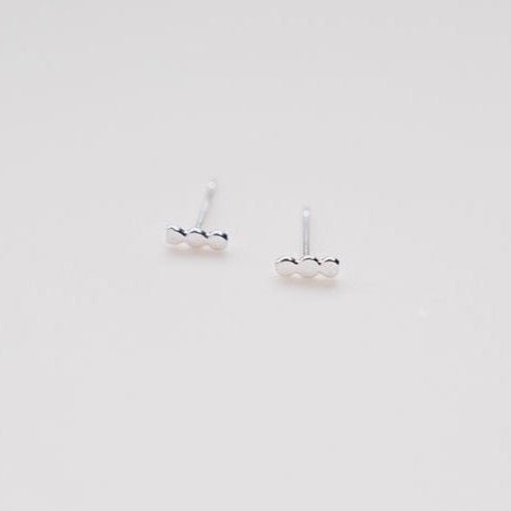 A sterling silver stud earring in a three dot pattern. The Three Dot Studs are designed and handcrafted by Deivi Arts Collective in Vancouver, Canada.