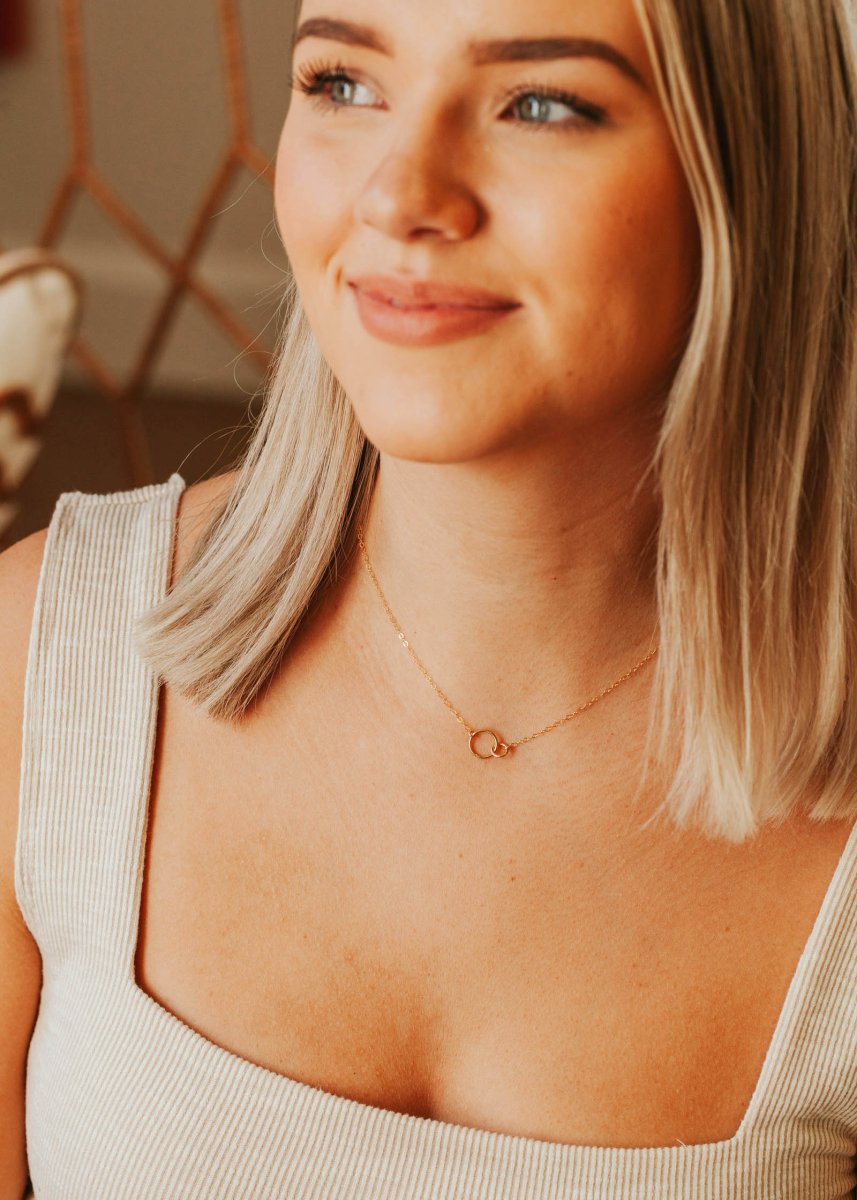 A models wears a dainty gold tone chain necklace connected with two tiny links. The Tiny Links Necklace is handcrafted by Hello Adorn in Eau Claire, WI.
