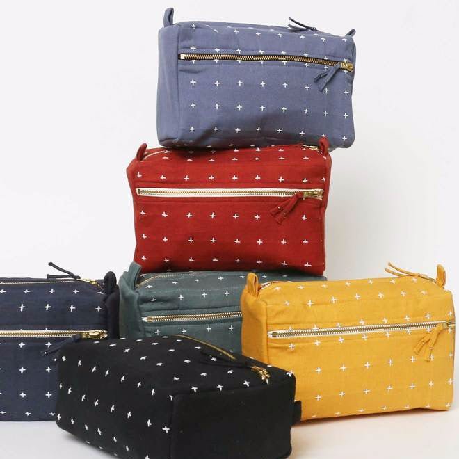 Square cross-stitch toiletry bags in assorted colors. Designed by Anchal in Louisville, Kentucky and handmade in Ajmer, India.