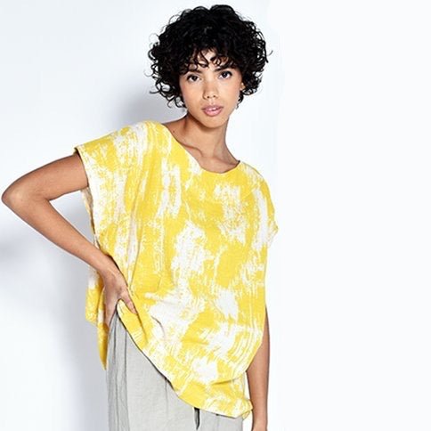 A model wears a short sleeve tunic with a bright yellow painted design. The Tun in Yellow Bark is designed by UZI NYC and sewn in Brooklyn, New York.