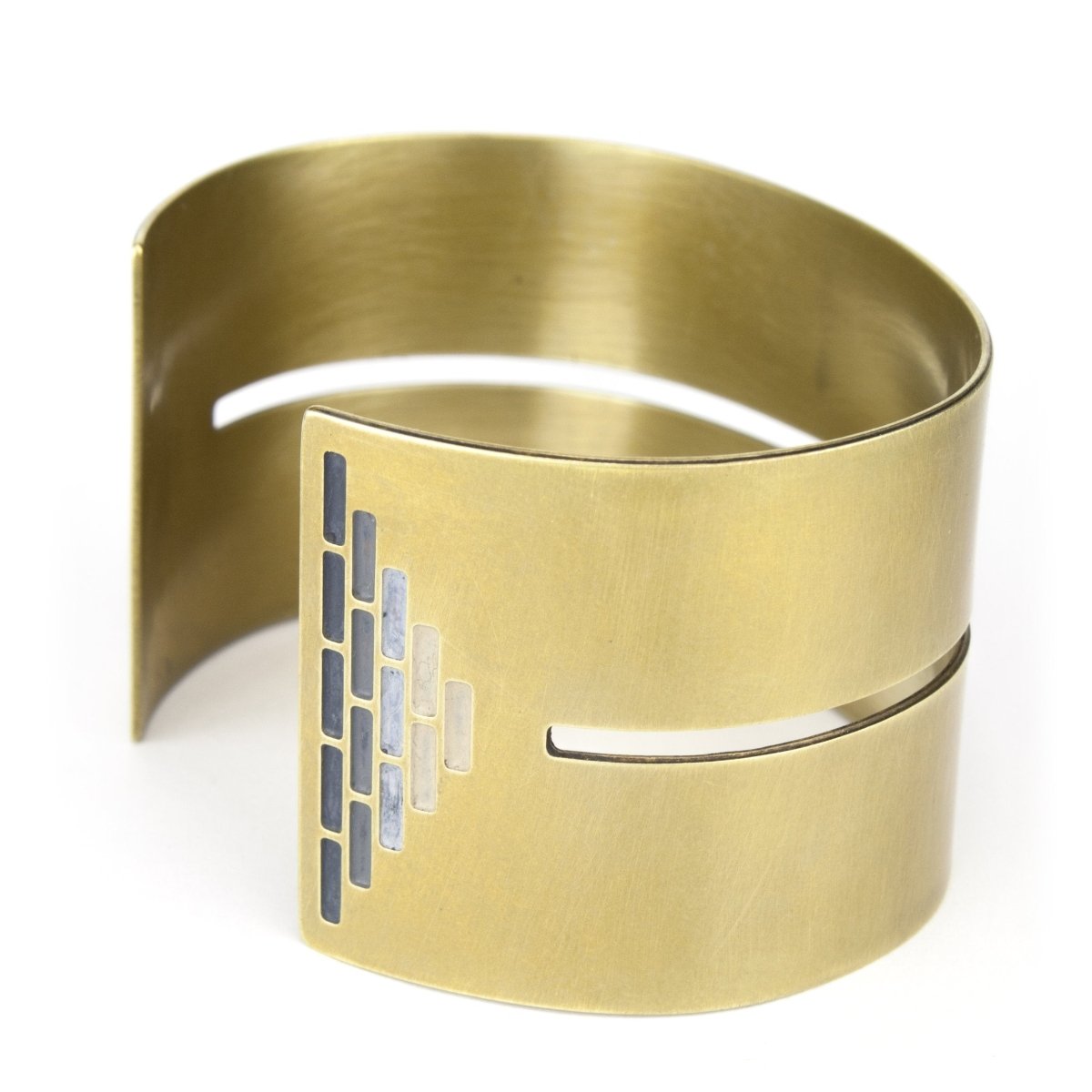 Wide, bold, brass cuff bracelet in the Portland colorway, with a cutout slit that runs through the center of the cuff and stops just short of a pyramid of grayscale paint on either end. Hand-crafted in Portland, Oregon.