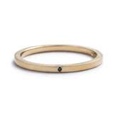 Thin, 14k yellow gold stacking band with a matte finish, and a tiny, round, flush-set black diamond. Hand-crafted in Portland, Oregon.