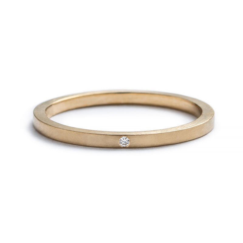 Thin, 14k yellow gold stacking band with a matte finish, and a tiny, round, flush-set white diamond. Hand-crafted in Portland, Oregon.