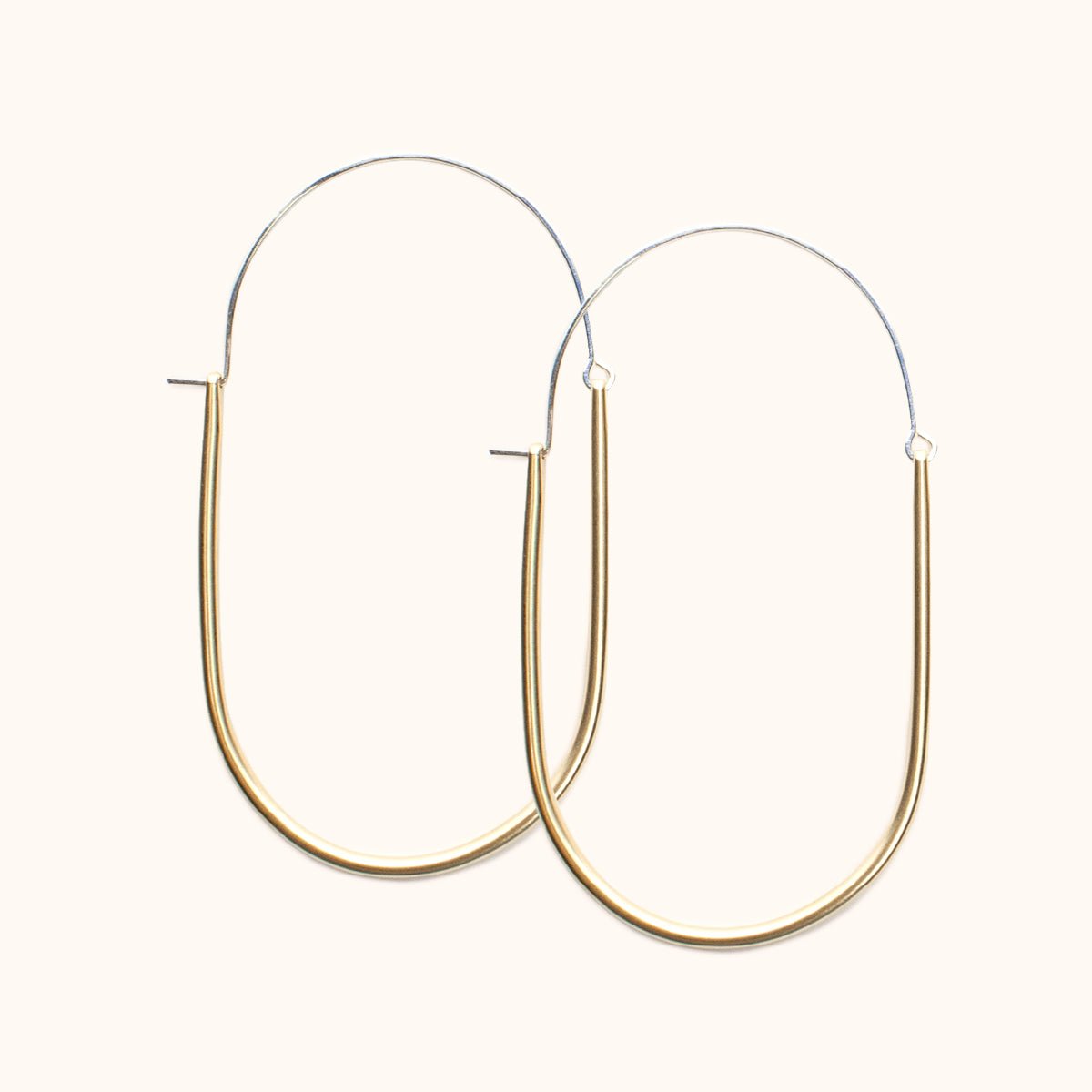 A large sterling silver and brass U-shaped earring with an arched ear wire that meets the top of the U. Designed and handcrafted in Portland, Oregon.