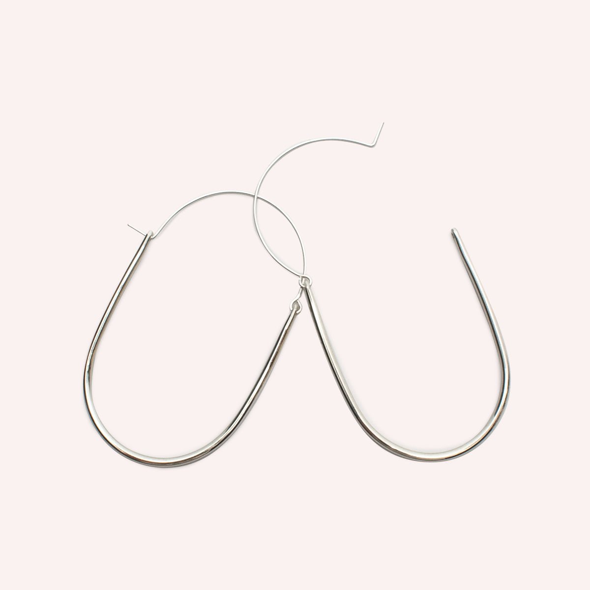 A large sterling silver U-shaped earring with an arched ear wire that meets the top of the U. One ear wire is unhooked and open. Designed and handcrafted in Portland, Oregon.