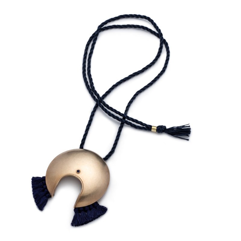 Large, circular, cast-bronze focal piece, featuring a u-shaped cutout at the bottom of the circle, a blue, bezel-set, lapis lazuli stone, and navy blue cotton fringe, threaded with an adjustable, navy blue cotton cord. Hand-crafted in Portland, Oregon.