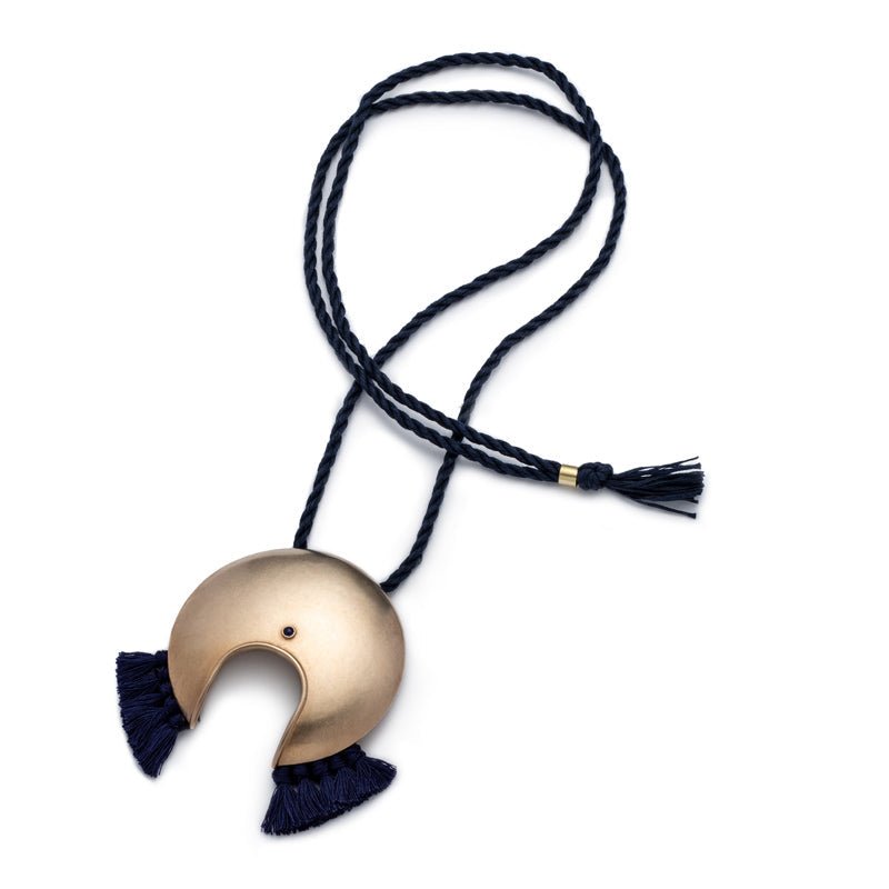 Large, circular, cast-bronze focal piece, featuring a u-shaped cutout at the bottom of the circle, a blue, bezel-set, lapis lazuli stone, and navy blue cotton fringe, threaded with an adjustable, navy blue cotton cord. Hand-crafted in Portland, Oregon.