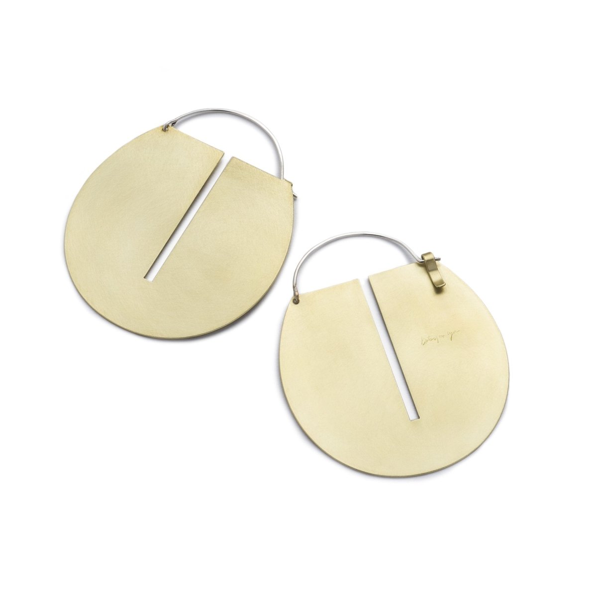 Large, round, brushed brass disc hoop earrings with a thin, rectangular cutout running down the center of the discs, and short, sterling silver earring wires that latch to the back of the discs. Hand-crafted in Portland, Oregon. 