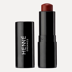 A tube of deep reddish lip tint. The Luxury Lip Tint in Intrigue is designed by Henné Organics and made in the USA.