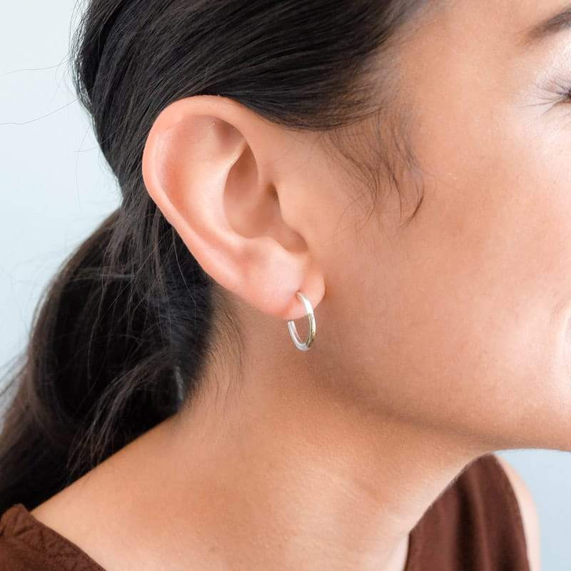 Betsy & iya mini, mixed-metal Koa hoop earrings, worn by a smiling model with straight, dark hair.