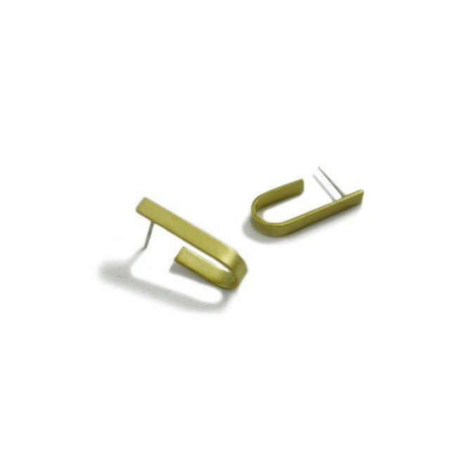 Two brass earrings against a white background. The earrings have a thin "U" shape made of brass and finished with silver posts. The Curved Line Ear Wrap Earrings are from designer Natalie Joy and made in Portland, Oregon.