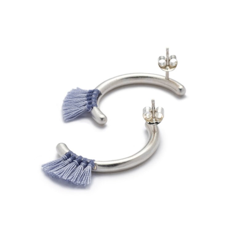 Modern, parentheses-shaped silver studs with light blue cotton fringe, sterling silver earring posts, and sterling silver ear nuts. Hand-crafted in Portland, Oregon.