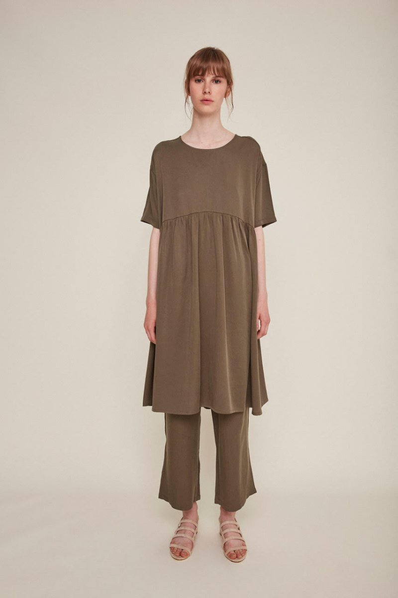 Red-haired woman wears a brown babydoll dress and matching pants. The Drapey Dress in Kaki is from designer Rita Row.