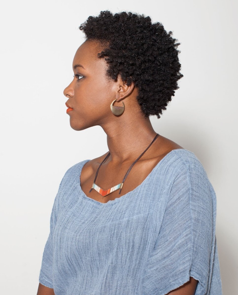 Bronze betsy & iya Portsmouth hoop earrings, styled on a model with a chambray tunic and a retired betsy & iya colorful statement necklace.