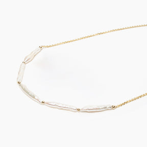 Gold necklace with pearl beads on a white background