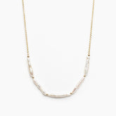 Gold necklace with five stick pearl beads on a white background