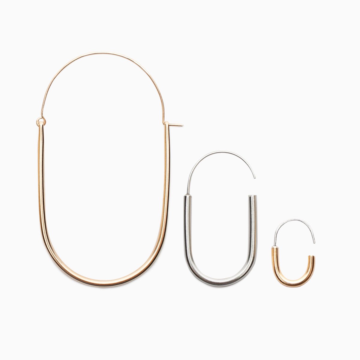 From left to righ: A large gold-fill U-shaped earring with an arched ear wire that meets the top of the U. A small sterling silver U-shaped earring with an arched sterling silver ear wire that leaves a slight opening. A mini brass hoop U-shaped earring with an arched sterling silver ear wire with a slight opening. Designed and handcrafted in Portland, Oregon.