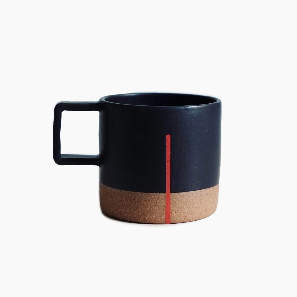 A matte black mug with a square handle and raw clay bottom portion. A thin red line runs vertically three-quarters of the way down. Designed and hand thrown by Wolf Ceramics in Hood River, Oregon.