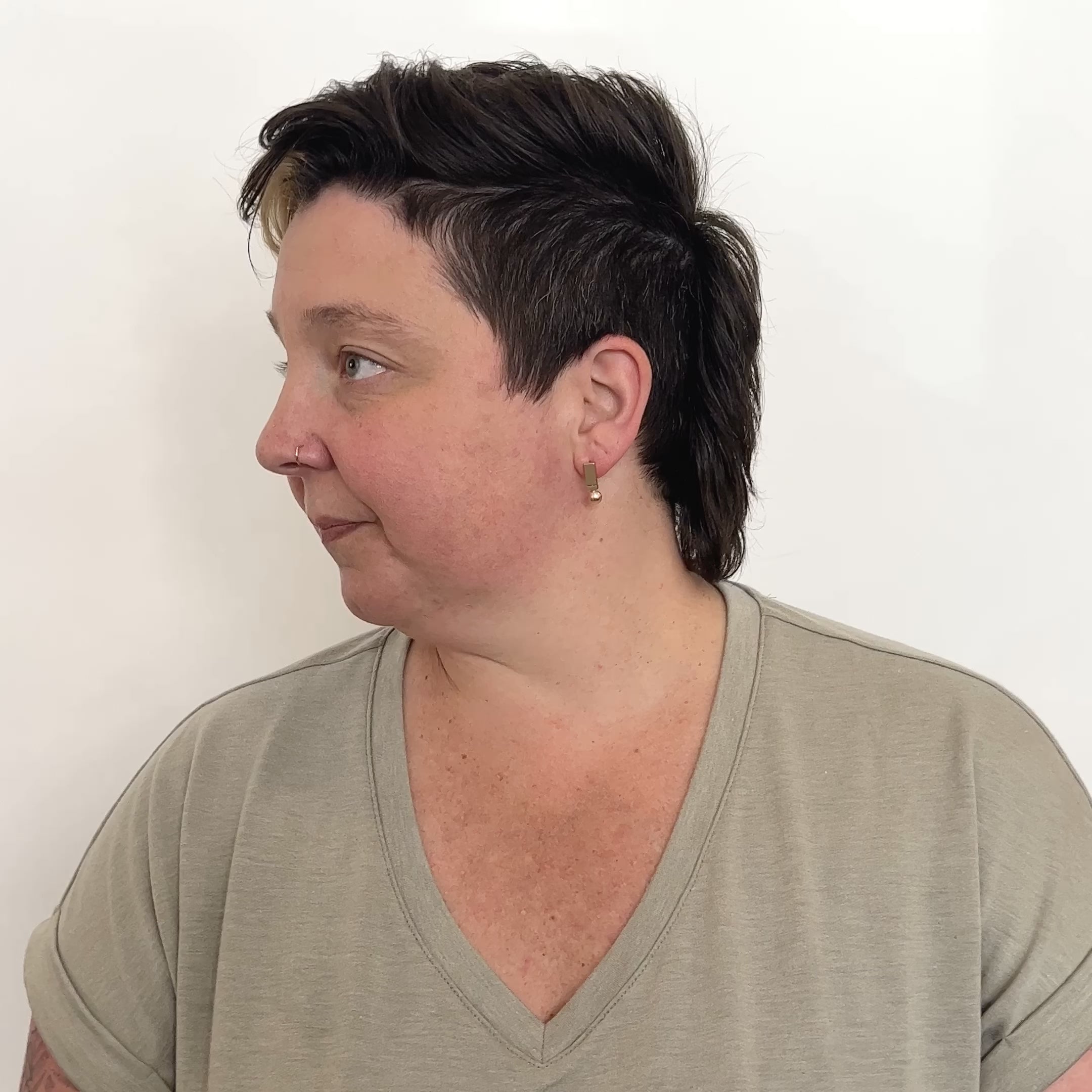 A model wears a bronze stud earring featuring a circular and rectangular shapes. They move their head from left to right. The Oriri Earrings are designed and handcrafted in Portland, Oregon.