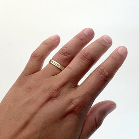 A model wears semi narrow 14k gold band on their ring finger. The band features a geometric stair step design. Designed and handcrafted in Portland, Oregon.