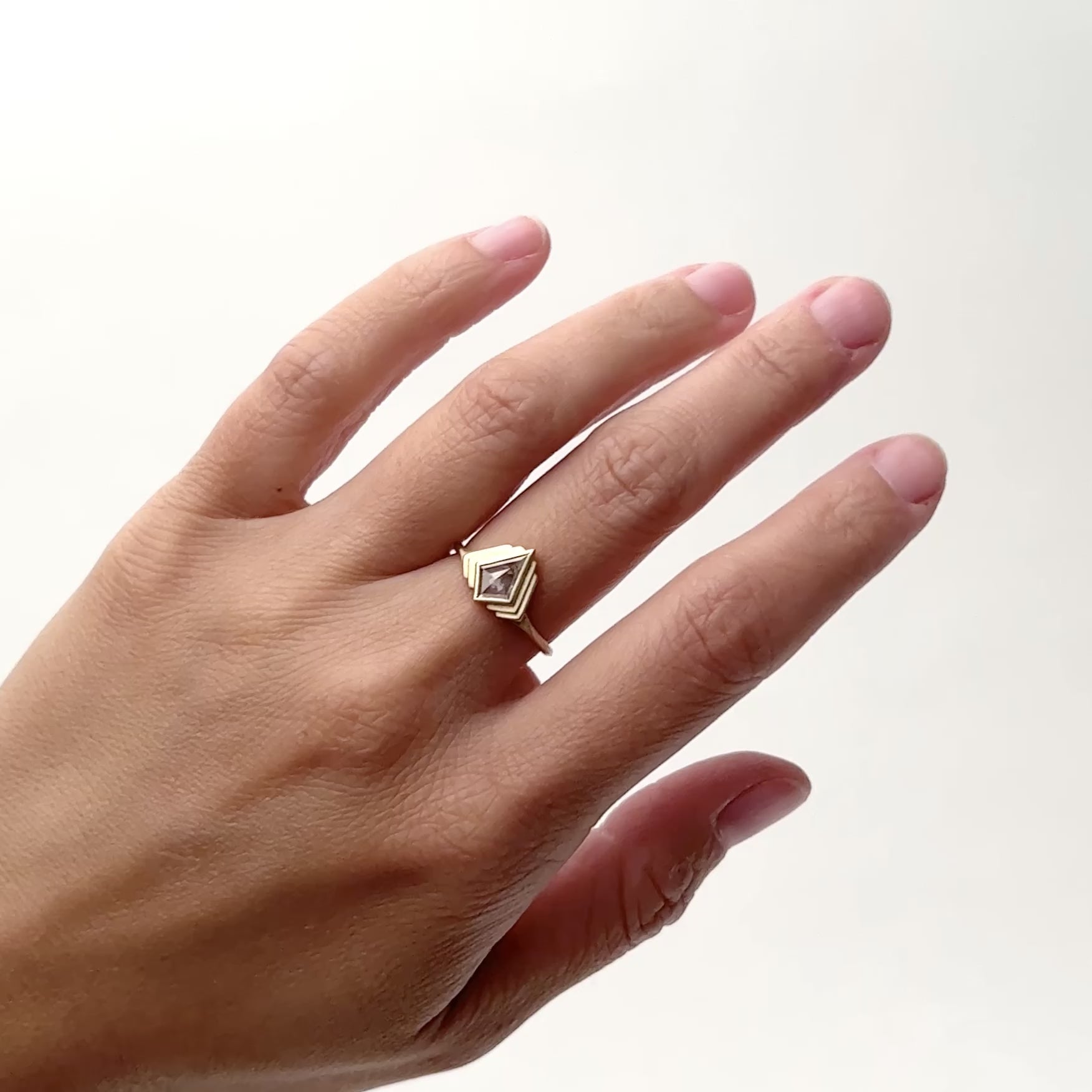 A model wears the Adra 14K recycled gold ring. This ring features a conflict free rosecut kite salt & pepper diamond. The model wears the Adra ring on their middle finger and rotates their hand from left to right. Designed and handcrafted in Portland, Oregon.