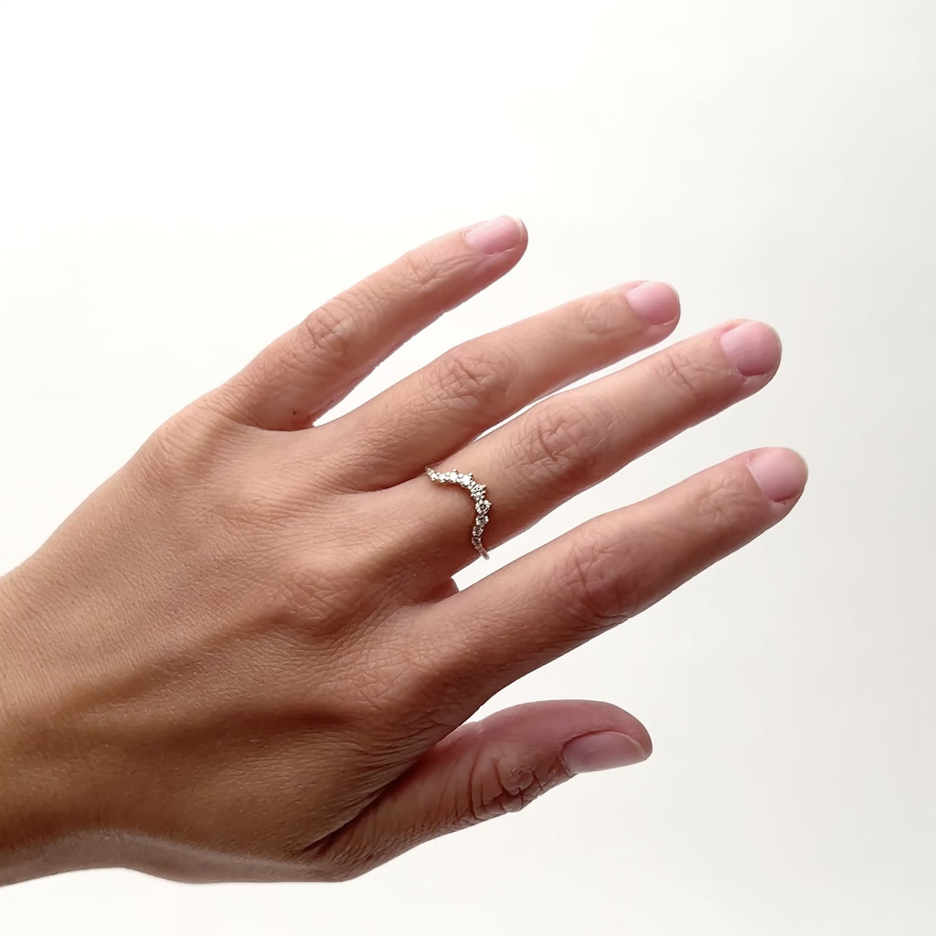 A rounded narrow band ring with 11 round brilliant cut lab grown diamonds. The model wears the Ortus ring on their middle finger as they rotate their hand from side to side. The Ortus ring is designed and handcrafted in Portland, Oregon.