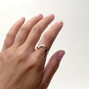 A model wears a flat, thin 14k yellow gold band in a rounded design on their pointer finger. This ring features five round cut lab grown white diamonds. Designed and handcrafted in Portland, Oregon.
