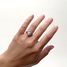 A model wears a rounded narrow band ring with 11 round brilliant cut lab grown diamonds. The model wears the Ortus ring with the 2 carat Salire ring on their left hand ring finger. They rotate their hand from side to side. The Ortus ring and the 2 carat Salire ring is designed and handcrafted in Portland, Oregon.