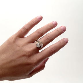 A model wears a 14k gold ring that features eight white diamonds each in an east/west orientation. The diamonds overlap to form a V shape. It sits with a hexagon shaped salt and pepper diamond ring with a Y shaped shank. Designed and handcrafted in Portland, Oregon.