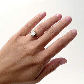 A model wears an 1.75ct emerald cut white diamond ring bezel set in 14k yellow gold. The setting shows cut outs on the north and south sides of the setting. Designed and handcrafted in Portland, Oregon.
