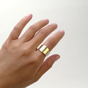 A model wears a wide band gold ring on their left pointer finger and shifts their hand from side to side. The center of the bands holds a very small channel of lab grown white diamonds going vertical on the band. The Decus ring is designed and handcrafted in Portland, Oregon. 