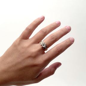 A model moves their hand from side to side wearing a 14k gold ring that features a large square cut diamond. Flanking the diamond on each side are two gold shaped arrows, one of which holds a setting of diamonds and the other is plan gold. Capping off the arrows is a single gold bar in a north-south orientation. Designed and handcrafted in Portland, Oregon.