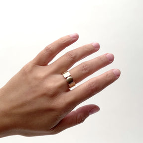 A model wears a wide band 14k gold. The shape of the band shows a circle and square side by side. The rest of the band is in equal width of the shapes but solid. Designed and handcrafted in Portland, Oregon.