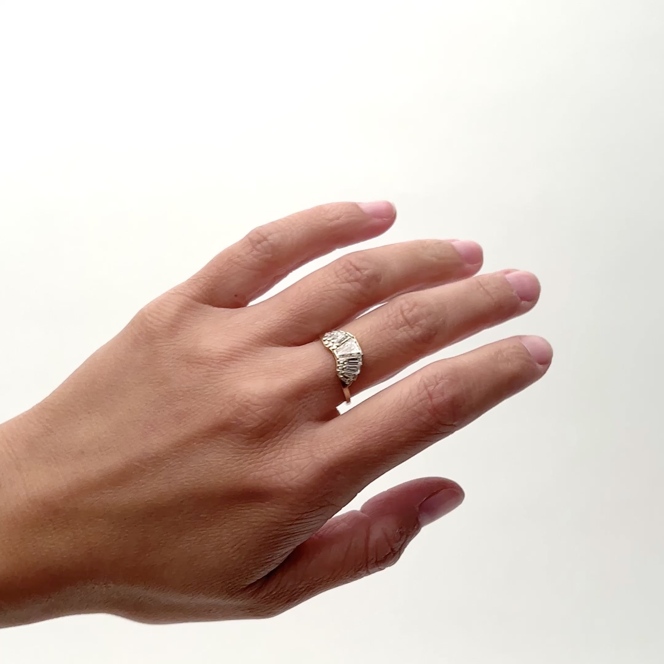 Model wears a fan shaped 14k gold ring with a series of tapered baguettes on the surface. Designed and handcrafted in Portland, Oregon.