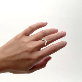 A model wears a 14k gold ring that features eight white diamonds each in an east/west orientation. The diamonds overlap to form a V shape. Designed hand handcrafted in Portland, Oregon. 