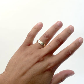 A model wears square wide band 14k gold ring in a polished finished. Delicate etched lines mark the top portion of the ring. Designed and handcrafted in Portland, Oregon.