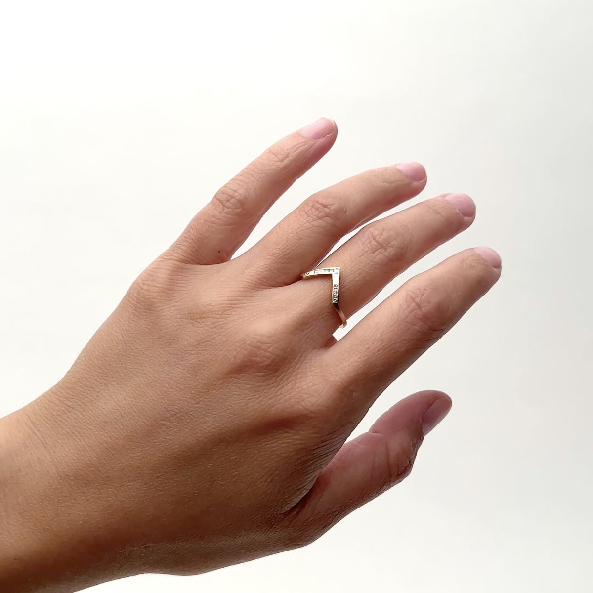 A model wears a V-shaped Altus 14K recycled gold stacking ring, with lab-grown diamonds on their middle finger. They roatet their hand from left to right. Designed and handcrafted in Portland, Oregon.