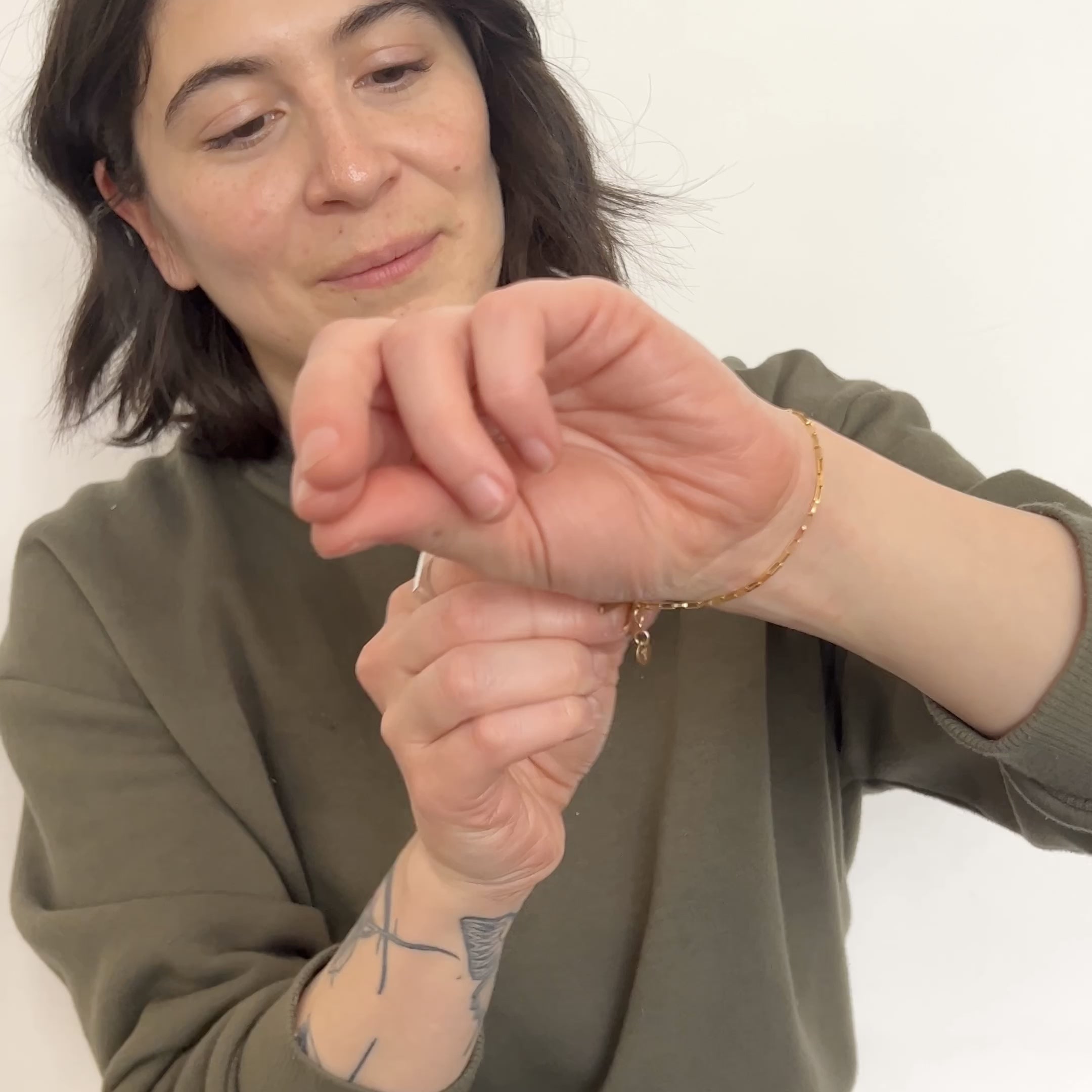 A model clasps a delicate gold-fill chain bracelet on their wrist. The Alba Bracelet is designed and handcrafted in Portland, Oregon.