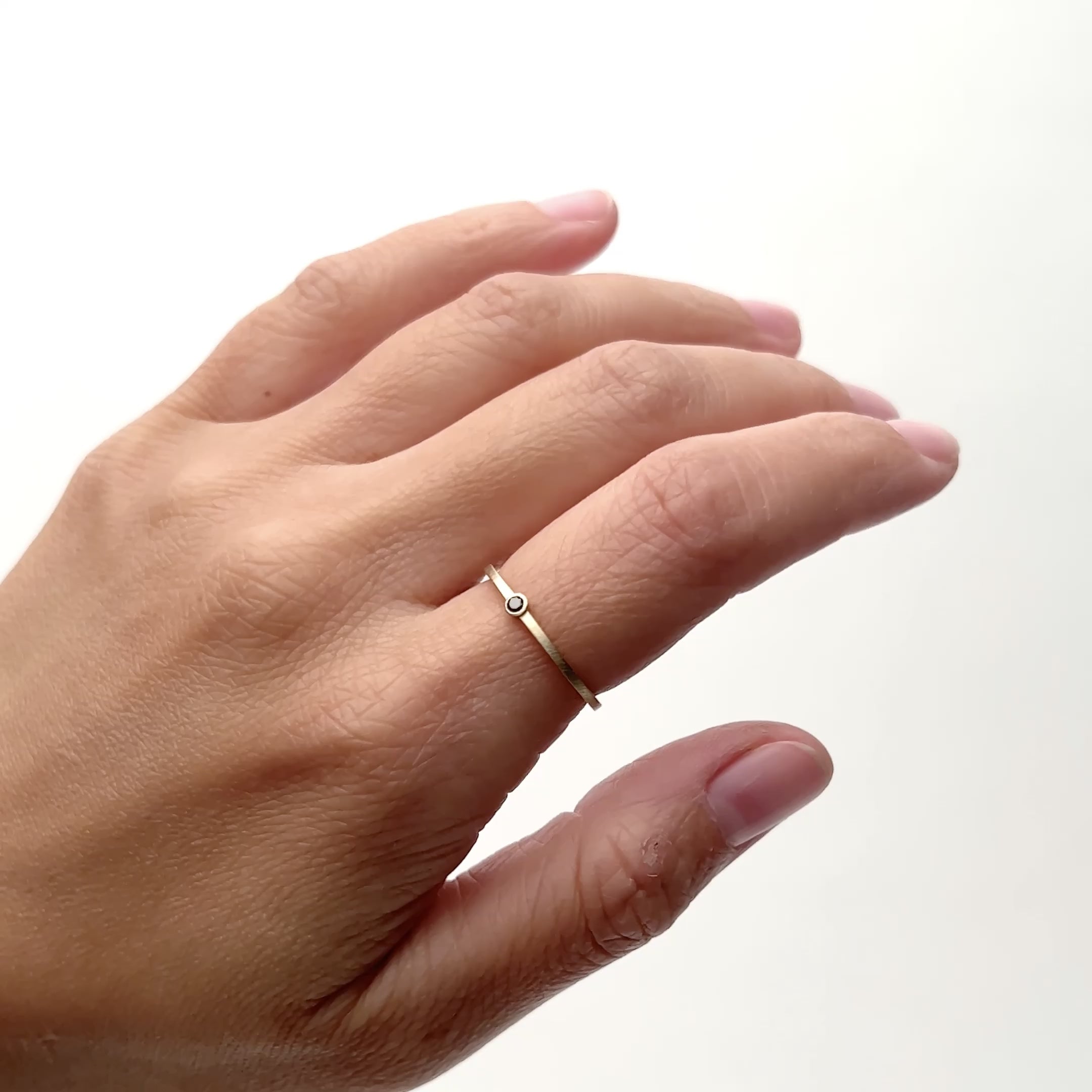 A model wears an ultra thin 14k yellow gold band with a round black diamond in the center. The Robur ring is designed and handcrafted in Portland, Oregon.,
