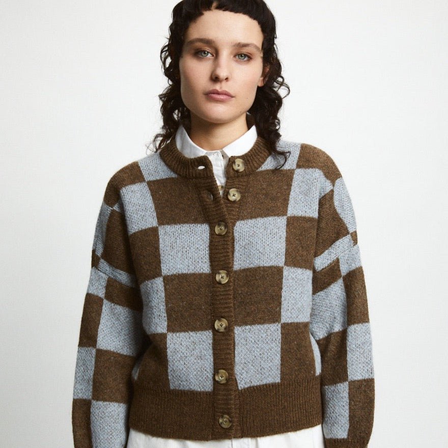 A model wears a knitted button up cardigan in a brown and light blue pattern. The Ellen Sweater in Brown + Blue is designed by Rita Row and made in Girona, Spain.