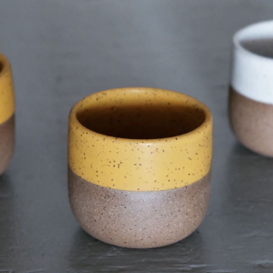 Speckled ceramic cup with matte yellow collar around rim and interior. Designed and hand thrown by Wolf Ceramics in Hood River, Oregon.