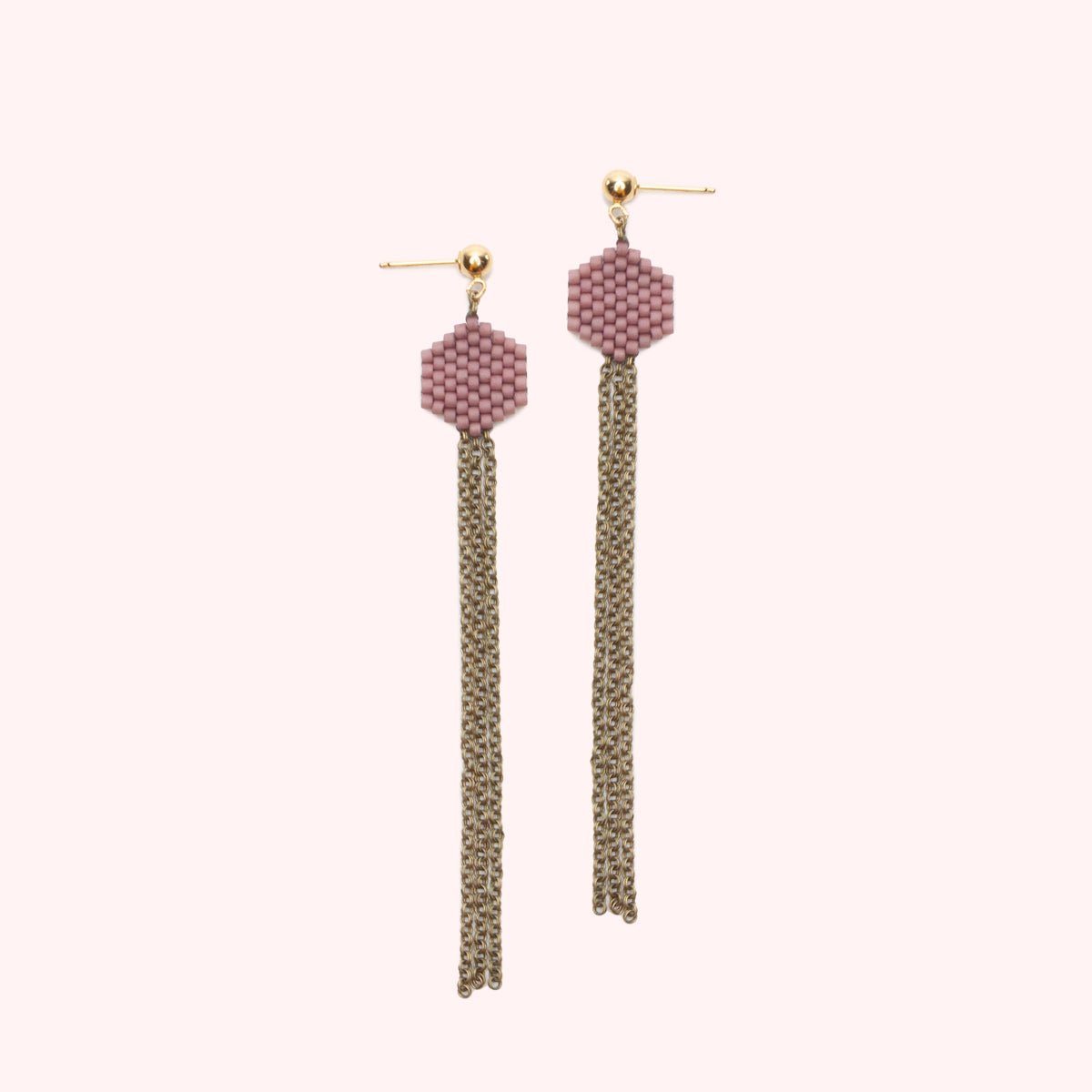 A gold-fill stud earring holds a small beaded hexagon in a mauve color. A narrow collection of antiqued brass chain hangs from the beaded portion. The Dot Earrings in Pink are designed and handcrafted by A Nod to Design in Portland, OR.