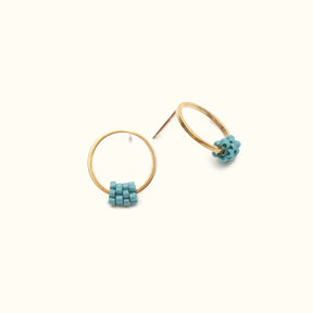 Petite circular brass stud ring, with a small bottom portion wrapped with light blue colored glass beads. The Fei Stud earrings in Nile Blue are designed by A Nod To Design and handmade in Portland, Oregon.