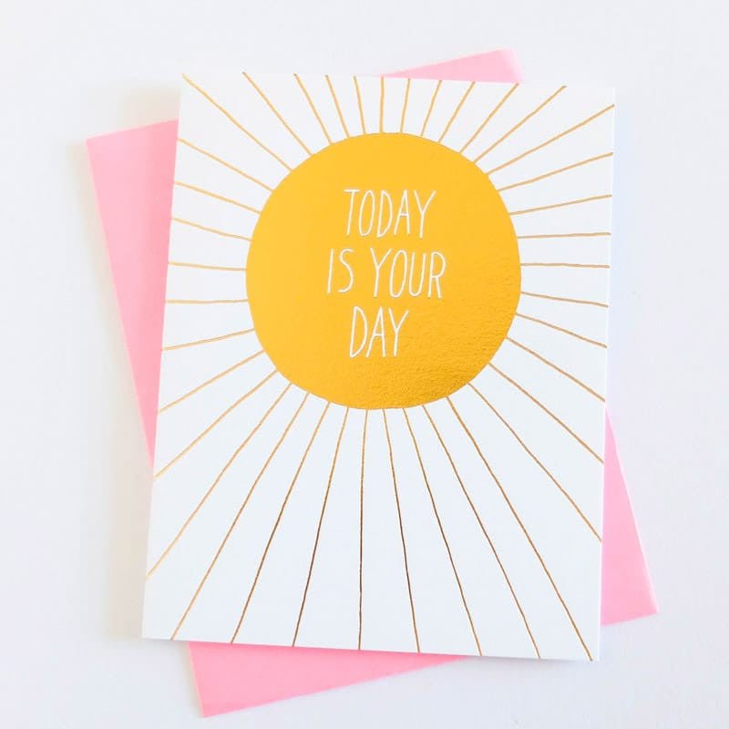 White card with iridescent yellow circular center and iridescent rays extending out. Center of card reads: "TODAY IS YOUR DAY." Comes with a pink envelope. Designed by Ashkahn and printed in Portland, OR.