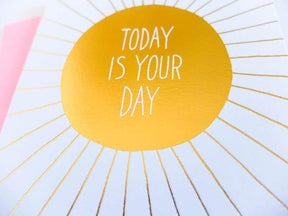 White card with iridescent yellow circular center and iridescent rays extending out. Center of card reads: "TODAY IS YOUR DAY." Comes with a pink envelope. Designed by Ashkahn and printed in Portland, OR.